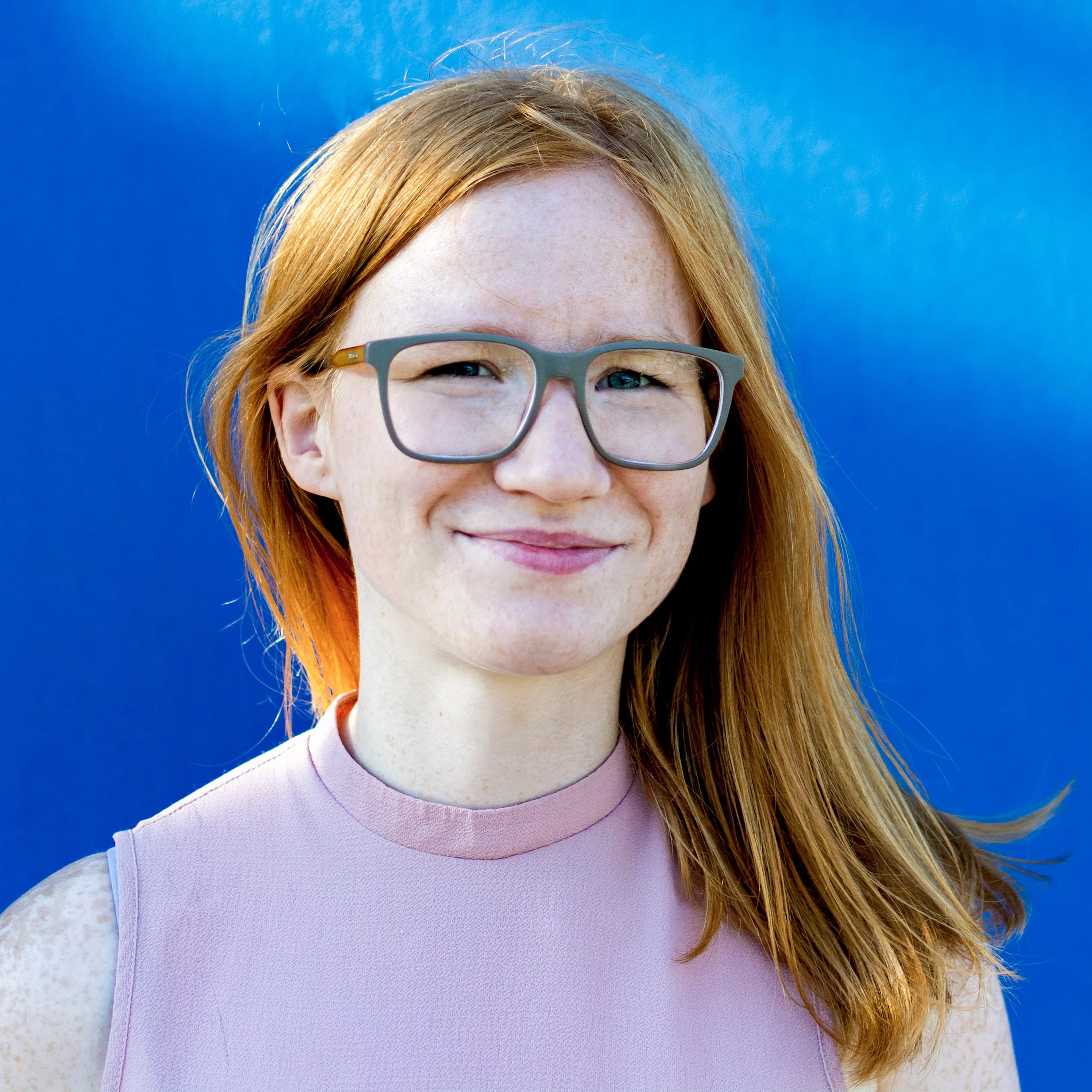 Jeune femme à la peau blanche et les cheveux roux portant des lunettes vertes